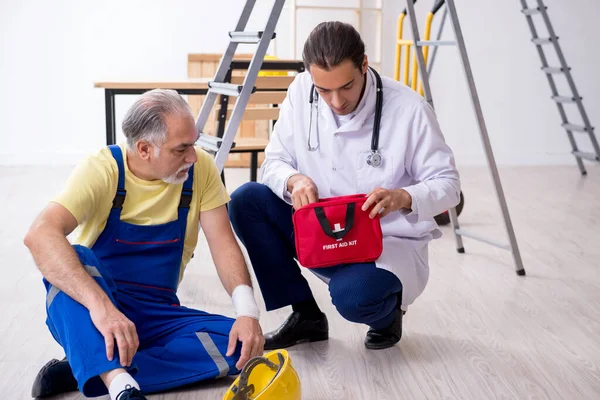 Giovane medico di sesso maschile e vecchio appaltatore nel concetto di pronto soccorso — Foto Stock