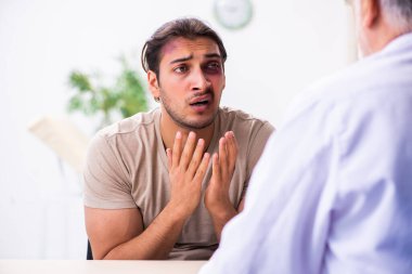 Yaralı genç adam deneyimli erkek doktor travmasını ziyaret ediyor.