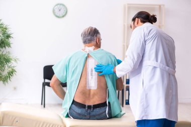 Yaşlı adam genç erkek doktoru ziyaret ediyor.