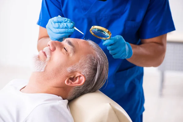 Anciano visitando joven doctor masculino en cono de trasplante de cabello — Foto de Stock