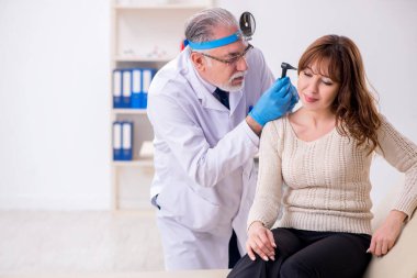 Genç bir kadın yaşlı erkek doktor otorhinolaryngologist 'i ziyaret ediyor.