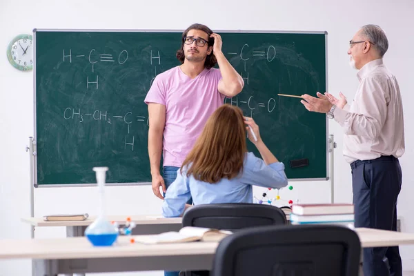 Régi kémikus tanár és két diák az osztályteremben. — Stock Fotó
