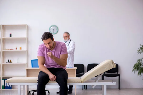 Joven paciente masculino visitando viejo médico masculino — Foto de Stock