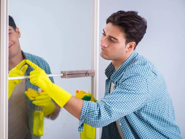 Giovane uomo specchio di pulizia a casa hotel — Foto Stock