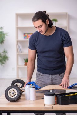 Kaykay tamir eden genç bir erkek tamirci.