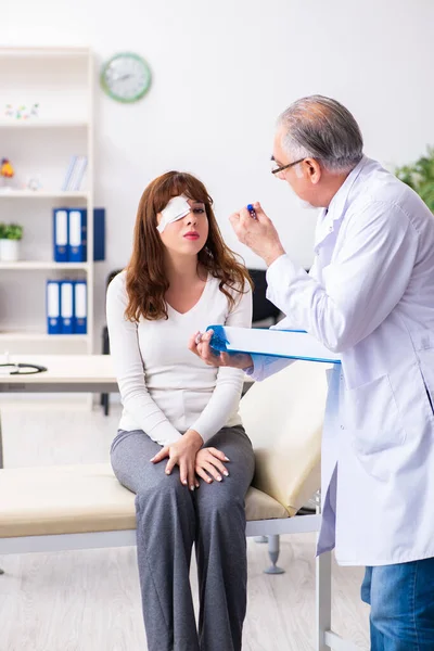 Młoda kobieta odwiedza starego lekarza okulistę — Zdjęcie stockowe