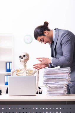 Genç erkek çalışan ve iskelet ofiste.