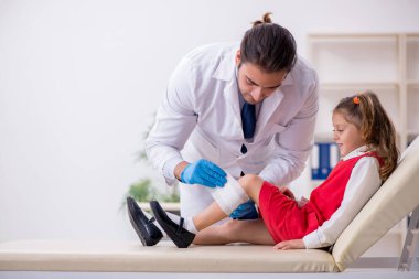 Küçük kız genç erkek doktoru ziyaret ediyor.