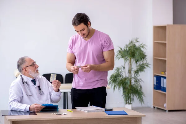 Genç erkek hasta yaşlı erkek doktoru ziyaret ediyor. — Stok fotoğraf