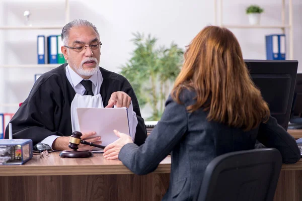 Oude mannelijke rechter en vrouwelijke cliënt in het kantoor — Stockfoto