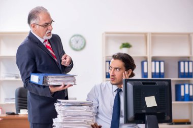 Eski patron ve genç erkek çalışan ofiste.