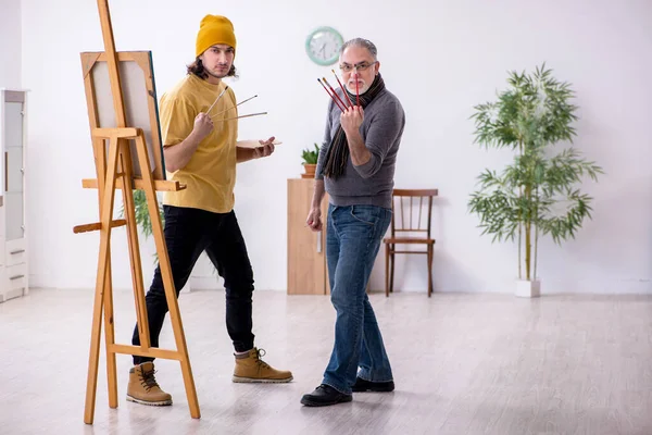 Old man taking lesson from young painter