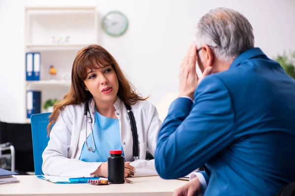 Oude zakenman bezoekt jonge vrouwelijke arts — Stockfoto