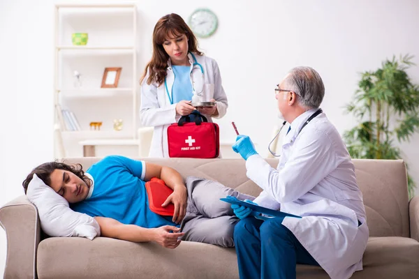 Zwei Ärzte besuchen kranken jungen Mann zu Hause — Stockfoto