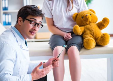 Doktor genç kızları çekiçle kontrol ediyor.