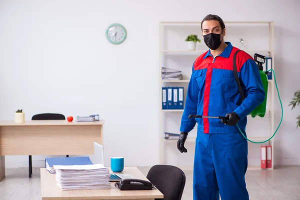 Contratista masculino joven desinfectando oficina —  Fotos de Stock