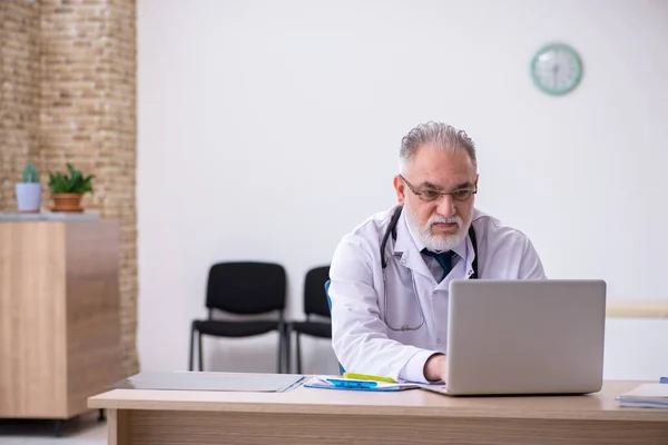 Oude mannelijke arts werkzaam in de kliniek — Stockfoto