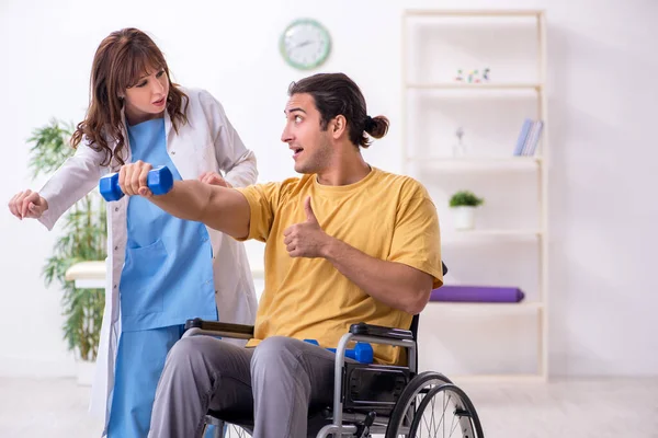 Jonge mannelijke patiënt in rolstoel die lichamelijke oefeningen doet — Stockfoto