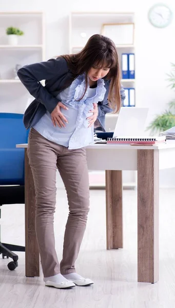 Mujer embarazada luchando para hacer el trabajo en la oficina — Foto de Stock