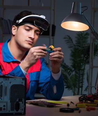 Bilgisayar uzmanı gece geç saatlerde bilgisayarı tamir ediyor.