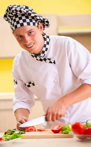 Jovem cozinheiro profissional preparando salada na cozinha — Fotografia de Stock