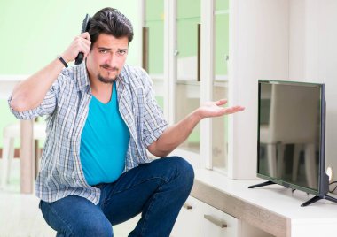 Genç adam evde televizyon tamir ediyor.