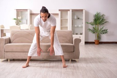 Genç adam evde fiziksel egzersiz yapıyor.