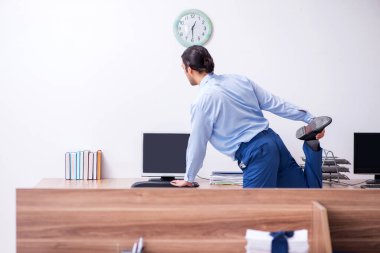 Genç yakışıklı işadamı iş yerinde egzersiz yapıyor.