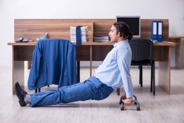 Genç yakışıklı işadamı iş yerinde egzersiz yapıyor.