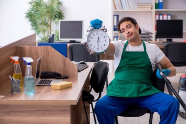 Genç yakışıklı müteahhit ofisi temizliyor.