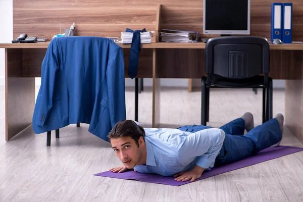 Jonge knappe zakenman doet oefeningen op het werk — Stockfoto