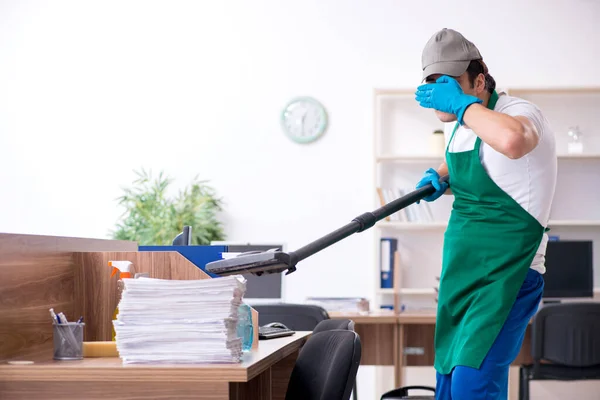 Jovem empreiteiro bonito limpando o escritório — Fotografia de Stock