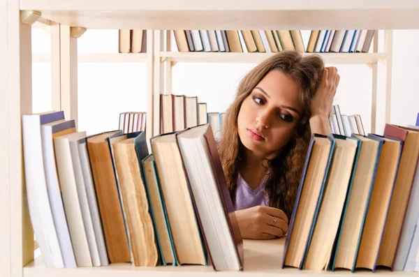 Ung kvinnlig student förbereder sig för tentamen på biblioteket — Stockfoto