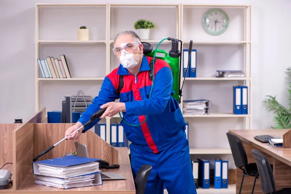 Oude professionele aannemer doet ongediertebestrijding in het kantoor — Stockfoto