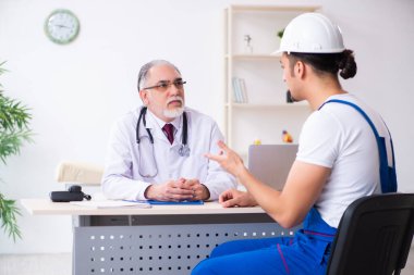 Genç erkek müteahhit yaşlı doktoru ziyaret ediyor.