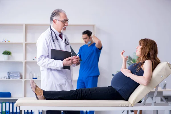 Dois médicos examinando jovem mulher — Fotografia de Stock