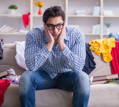 Genç adam dağınık bir odada çalışıyor.