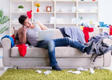 Genç adam dağınık bir odada çalışıyor.