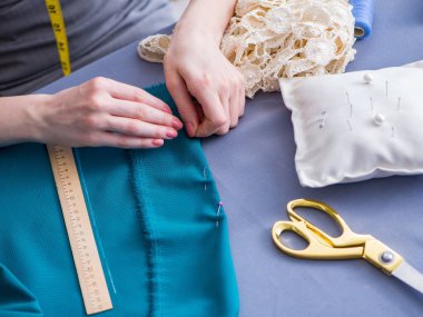 Kadın terzi dikiş dikmek için dikiş dikiyor.