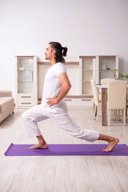 Genç adam evde fiziksel egzersiz yapıyor.