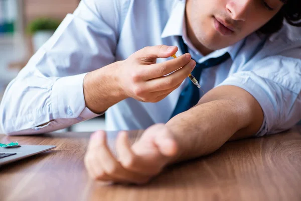 Young man having problems with narcotics at workplace — Stock Photo, Image