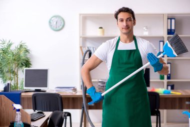 Genç yakışıklı müteahhit ofisi temizliyor.