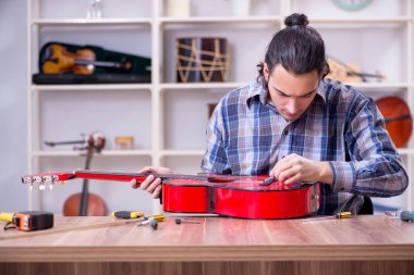 Gitarı tamir eden yakışıklı bir tamirci.