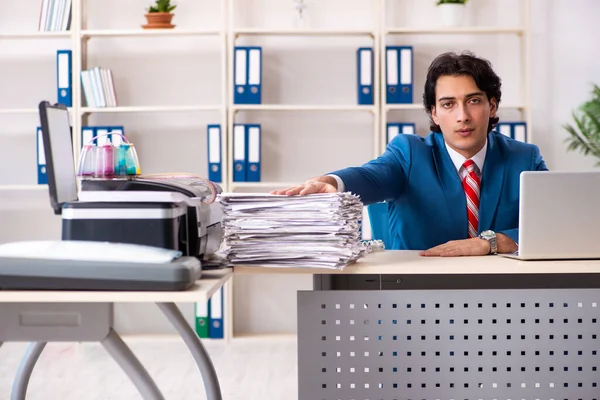 Jonge werknemer maakt kopieën bij kopieermachine — Stockfoto