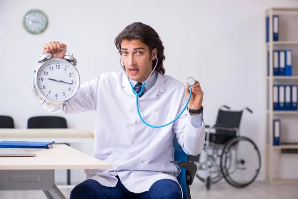 Joven médico masculino en concepto de gestión del tiempo —  Fotos de Stock