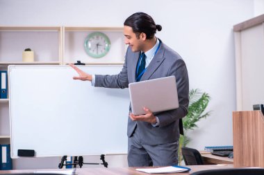 Genç işadamı beyaz panonun önünde duruyor.