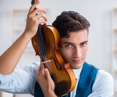 Genç müzisyen evde keman çalıyor.