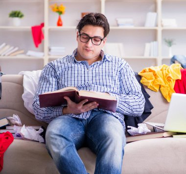 Genç adam dağınık bir odada çalışıyor.