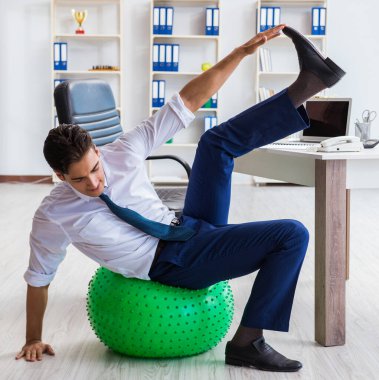 Genç işadamı iş yerinde spor yapıyor.