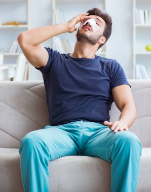 Genç adam estetik cerrahi burnundan sonra evde iyileşiyor.